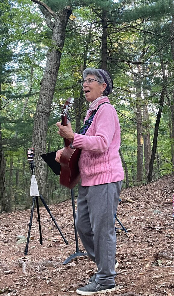 Suri playing the guitar on a nature trail